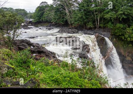 Hilo, Hawai, Estados Unidos. - 14 de enero de 2020: El agua corre sobre el borde de White Rainbow Falls en el río Wailuku rodeado de árboles y plantas verdes. Foto de stock