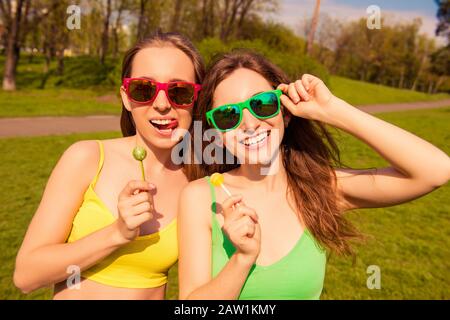 Atractivas y alegres niñas sonrientes con caminar en el parque con lollipops Foto de stock