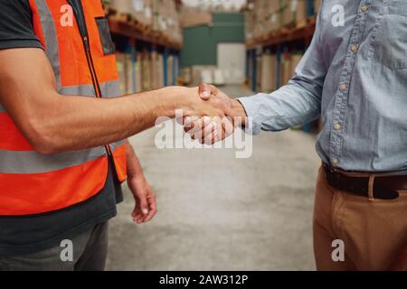 Primer plano de la foto de un apretón de manos en ropa formal y uniforme en almacén