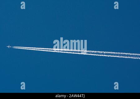 Un avión de reacción deja senderos de vapor, o contraílos, que se extienden a través del cielo. Foto de stock