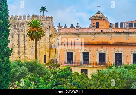 La vista sobre la torre de piedra Homage y el palacio ocre Villavicencio a través de la exuberante vegetación del jardín del Alcázar, Jerez, España