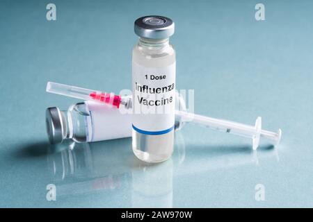 Vacuna contra la gripe aviar Los viales con la jeringa sobre fondo turquesa Foto de stock