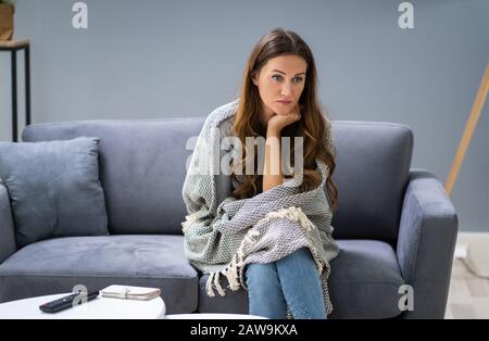 Pisado joven mujer sentada en un sofá en casa