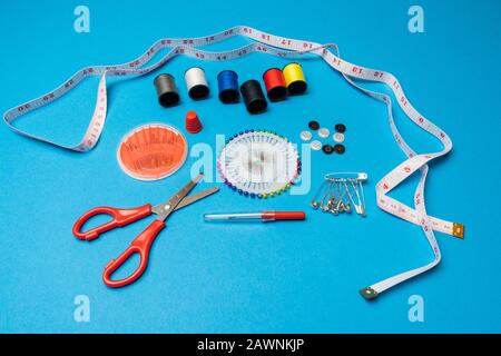 Carretes de hilo y herramientas básicas de costura incluyendo pasadores, aguja, un dedal y cinta métrica. Espacio de copia. Formato de banner largo Foto de stock