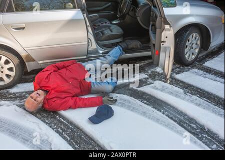 El hombre mayor se deslizó sobre el hielo saliendo de su coche Foto de stock