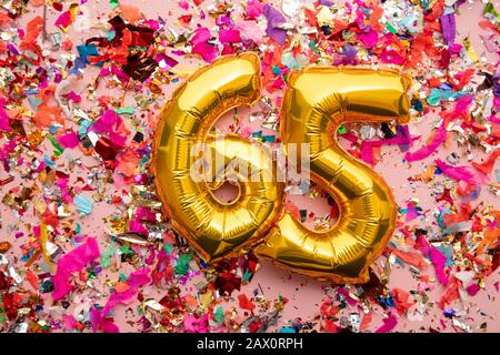 Número 65 oro cumpleaños celebración globo sobre un fondo brillante confetti Foto de stock