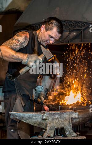 Martillo De Herrero Golpea El Metal Caliente. Forja De Objetos De Hierro En  Una Fragua Retro. El Proceso De Trabajo En La Fabricación De Armas Herrero  En El Yunque. Fotos, retratos, imágenes