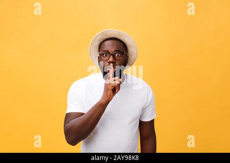 Closeup retrato de apuesto hombre calvo colocando el dedo sobre los labios como para decir, aislado sobre fondo amarillo con espacio de copia Foto de stock