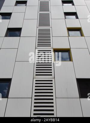 primer plano de paneles de revestimiento de metal de color plata en un edificio moderno con ventanas repetidas y diseño geométrico de cuadrícula Foto de stock