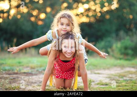Dos niñas Cute jugando y riendo en el campo. Feliz concepto de los niños al aire libre