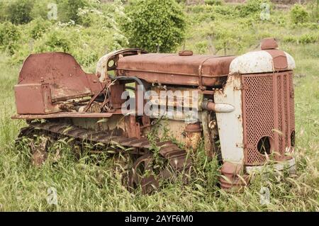 Viejo descuidado rusty pequeño vintage caterpillar tractor sobre verde pradera Foto de stock