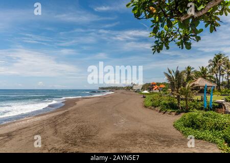 Vista De Pantai Babadan (Playa Babadan), Bali, Indonesia. Arena negra volcánica, océano, olas, palmeras.
