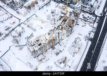 nuevo edificio de apartamentos en construcción. dos grúas torre trabajando en la obra en invierno. vista aérea