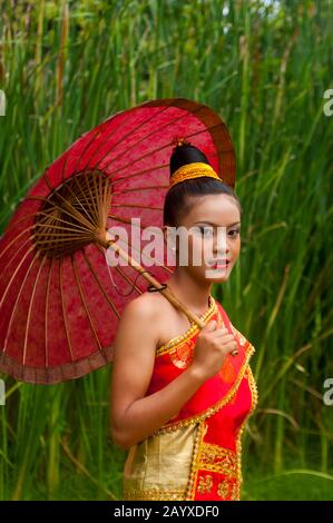 Una adolescente laosiana (VERSIÓN MODELO 2006-10-04) en un traje festivo tradicional De Las Tierras Bajas con sombrilla en el jardín de la Residence Phou Vao Hot Foto de stock