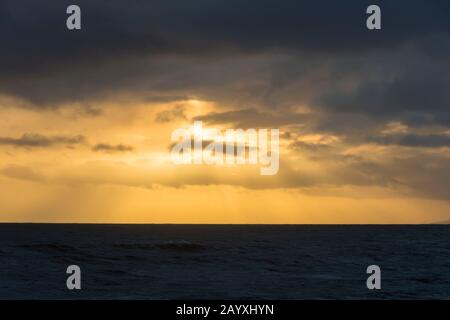 West Bay, Dorset, Reino Unido. 17 de febrero de 2020. El tiempo en Reino Unido. El sol poniente detrás de nubes de ducha oscuras poco antes de la puesta de sol en West Bay en Dorset. Crédito De La Imagen: Graham Hunt/Alamy Live News Foto de stock