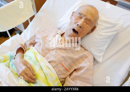 Paciente de anciano japonés acostado en la cama durmiendo en el hospital