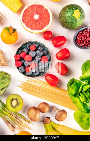 Alimentos veganos, dieta saludable plana. Frutas, verduras, legumbres, setas, pasta, inyectadas desde arriba sobre un fondo blanco Foto de stock