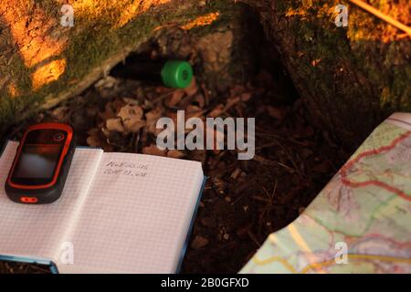 búsqueda de un geocaché en el bosque con la ayuda de un dispositivo gps, un mapa y un portátil Foto de stock