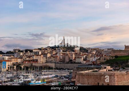 Marsella, Francia - 25 de enero de 2020: La vista de la Basílica Notre-Dame de la Garde y el antiguo puerto al atardecer