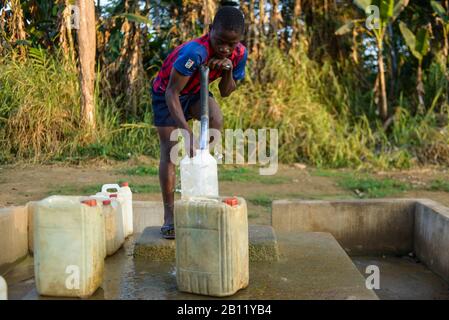 El niño extrae agua de un pozo, la selva ecuatorial, Gabón, África Central Foto de stock