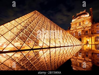 París - 25 DE SEPTIEMBRE de 2013: La famosa pirámide de cristal en el Louvre. El Louvre es uno de los museos más grandes del mundo y uno de los principales turistas