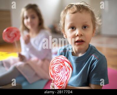 Dos niños juegan y comen lolypops Foto de stock