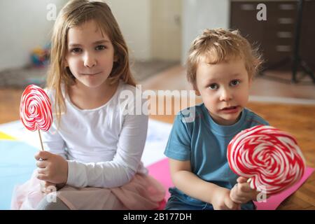 Dos niños juegan y comen lolypops Foto de stock