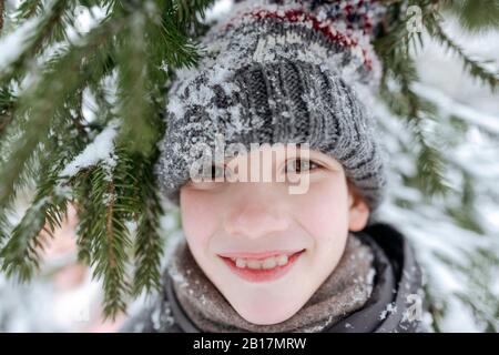 Retrato de un niño sonriente que se divierte en el bosque de invierno Foto de stock