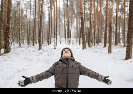 Niño atrapando copos de nieve en el bosque de invierno Foto de stock