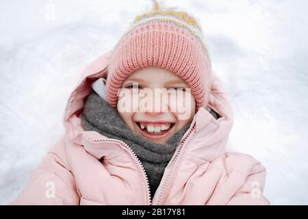 Retrato de una chica feliz tumbada en la nieve Foto de stock