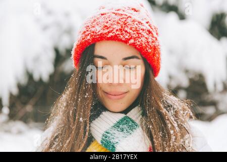 Retrato de una mujer sonriente con los ojos cerrados en invierno Foto de stock