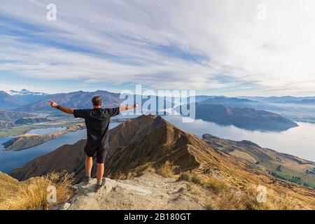 Excursionista de pie en el mirador de Roys Peak, mirando al Monte aspirante, Lago Wanaka, Isla del Sur, Nueva Zelanda