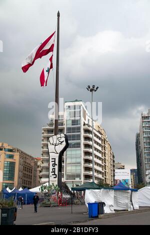 Bandera libanesa y monumento revolucionario de la mano levantado en la plaza Martyr en el centro de Beirut donde las protestas y las manifestaciones están teniendo lugar Foto de stock