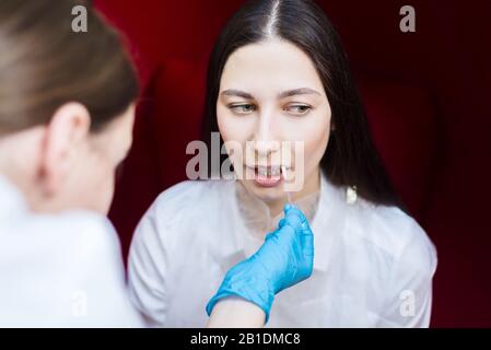 niña en el salón de belleza. El médico humidifica el gel de labios. Higiene odontológica Foto de stock