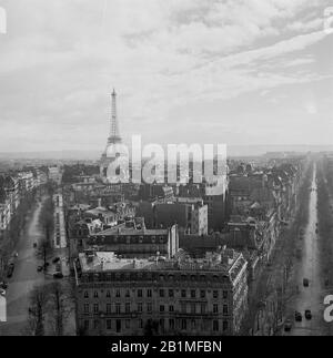 1950, vista aérea histórica sobre el horizonte de París, con el famoso monumento parisino, la Torre Eiffel en el Champ de Mars en la distancia. Construida en 1889 para la Feria Mundial, la torre de hierro forjado es una estructura icónica de la ciudad y considerada una maravilla arquitectónica. Foto de stock