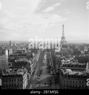 1950, vista aérea histórica sobre el horizonte de París, con el famoso monumento parisino, la Torre Eiffel en el Champ de Mars en la distancia. Construida en 1889 para la Feria Mundial, la torre de hierro forjado es una estructura icónica de la ciudad y considerada una maravilla arquitectónica. Foto de stock