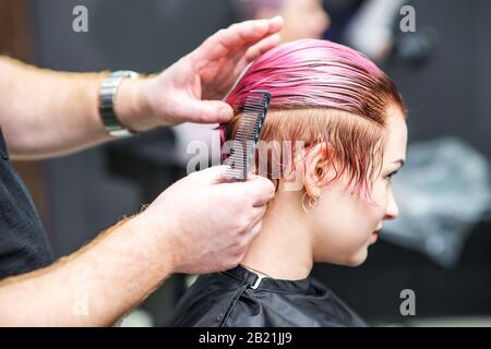 Primer plano de peluquería peinan el cabello de la mujer en el salón de belleza. Foto de stock
