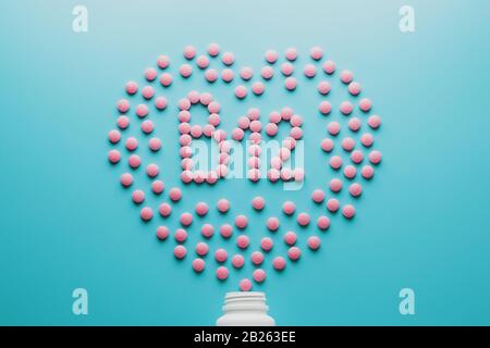 Tabletas rosadas en forma de B12 en el corazón sobre un fondo azul, derramadas de una lata blanca. Concepto de suplemento de comida