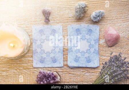 Cubierta con tarjetas de ángel de adivinación sobre mesa de madera clara, rodeada de cristales de piedras semipreciosas. Foto de stock