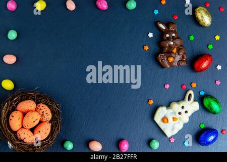 Huevos de Pascua en el nido, conejito de chocolate y huevos. Vista superior sobre mesa de piedra con espacio para sus saludos Foto de stock