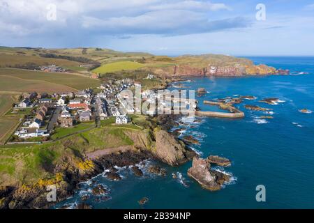 Vista aérea de un pequeño pueblo pesquero y el puerto de St Abbs en la costa del Mar del Norte en Scottish Borders, Escocia, Reino Unido Foto de stock