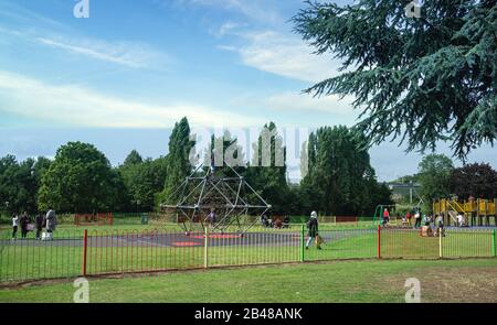 Los niños disfrutan de las áreas de juego en Salt Hill Park, Slough, mientras sus padres miran. Día soleado, a mediados de verano Foto de stock