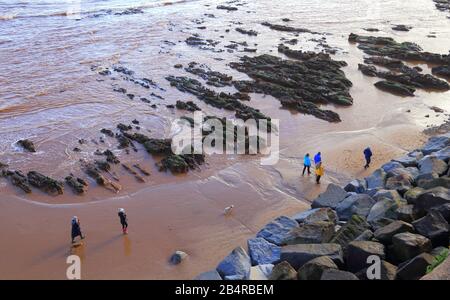 La gente camina por la playa de arena durante la marea baja en la ciudad de Sidmouth, Devon Foto de stock