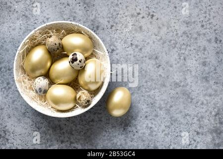 Huevos de pollo de Pascua dorados en un Bol sobre fondo de piedra gris. Vista desde arriba. Espacio de copia.