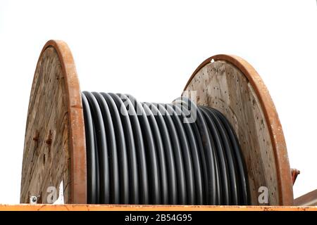 Un carrete o carrete de madera con cables de fibra óptica en un sitio de construcción, separado sobre un fondo blanco Foto de stock
