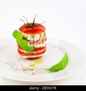 Concepto de comida italiana. Deliciosa ensalada Caprese con tomates maduros y queso mozzarella con hojas frescas de albahaca. Fondo blanco. Foto de stock