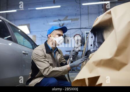 Plano medio horizontal del pintor profesional de automóviles en el trabajo de protección en el centro de servicio de automóviles, espacio de copia