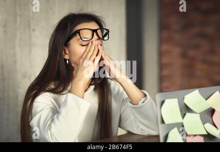 Mujer joven trabajando duro, quitándose las gafas Foto de stock