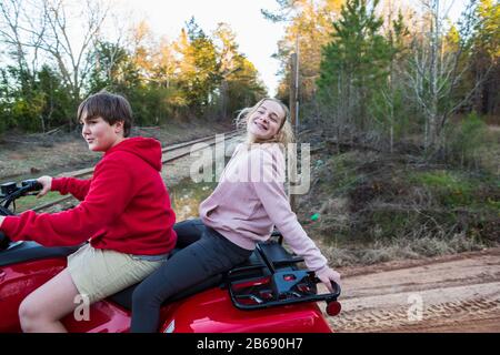 Dos adolescentes que viajan en un vehículo todoterreno en buggy por una pista fangosa. Foto de stock