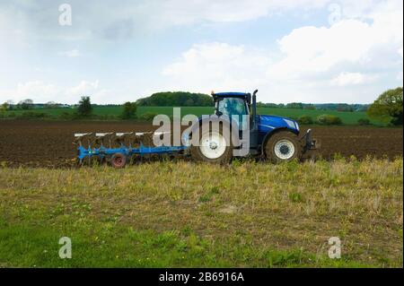 Un tractor que rema, arando en la rastrojo en un campo. Foto de stock